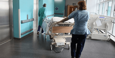 nurses wheeling an unseen person on a gurney in hospital
